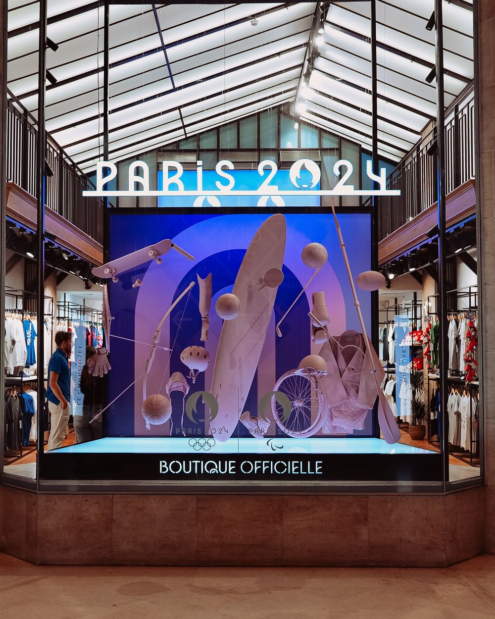 Window display of the Paris 2024 official store, staged with sports equipment